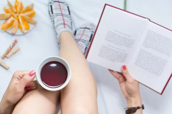 Donna che legge un libro e beve una tazza di tè — Foto Stock