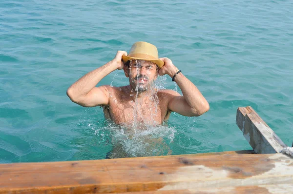 Man in sea wearing a hat full with water — Stock Photo, Image
