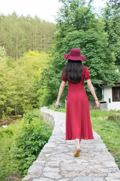 Kobieta spaceru ścieżką na sobie czerwoną sukienkę — Zdjęcie stockowe
