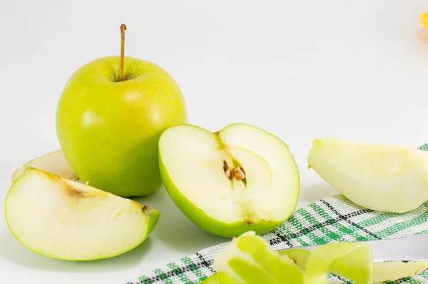 Целые и нарезанные зеленые яблоки на белом — стоковое фото