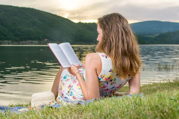 Uma mulher a ler um livro junto ao lago. Relaxamento individual — Fotografia de Stock