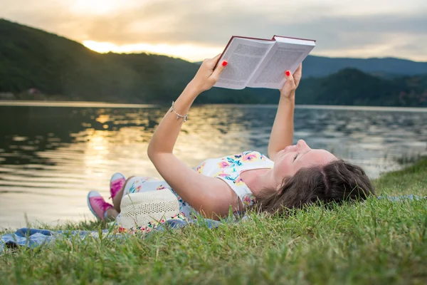 Uma mulher a ler um livro junto ao lago. Relaxamento individual — Fotografia de Stock