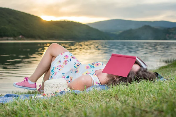 Uma mulher a dormir com um livro junto ao lago. Relaxamento individual — Fotografia de Stock