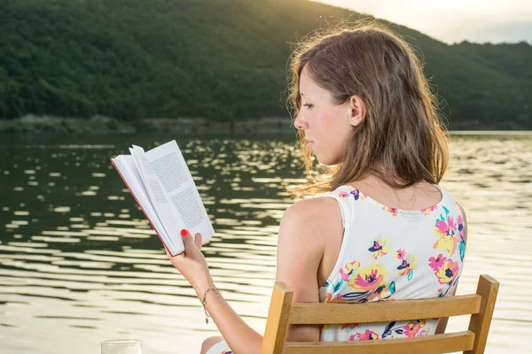 Mulher lendo um livro junto ao lago — Fotografia de Stock