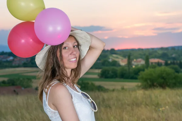 Молодая женщина держит воздушные шары на закате — стоковое фото