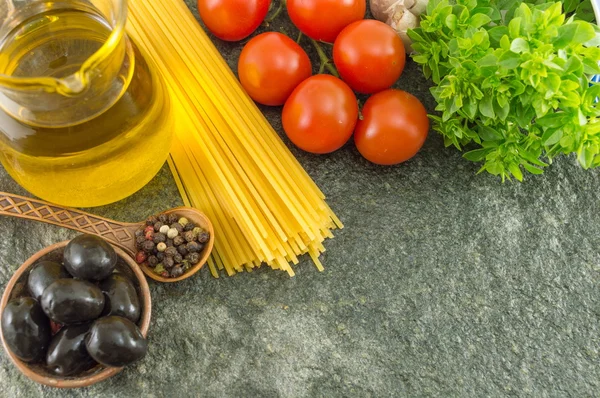 Spaghetti crudi con verdure un tavolo di pietra — Foto Stock