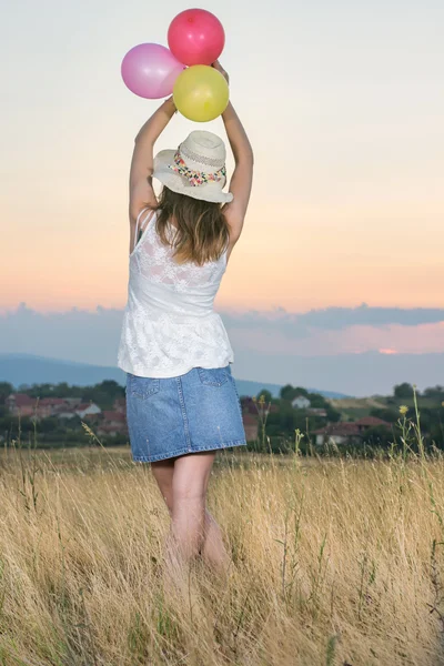 夕日を見て風船を保持している若い女性 — ストック写真