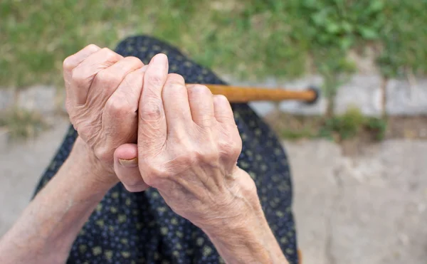 Alte Frauenhände halten einen Gehstock in der Hand — Stockfoto