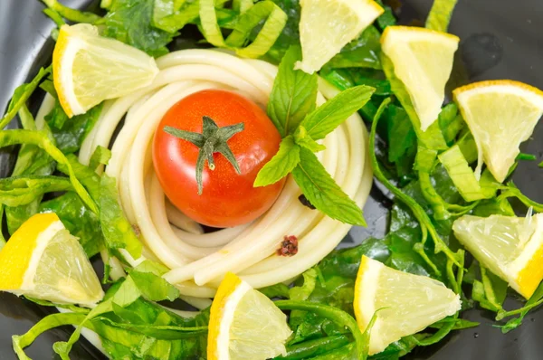 Spaghetti around small tomato with spices — Stock Photo, Image