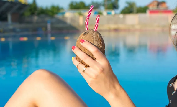 Женщина держит кокосовый коктейль у бассейна — стоковое фото