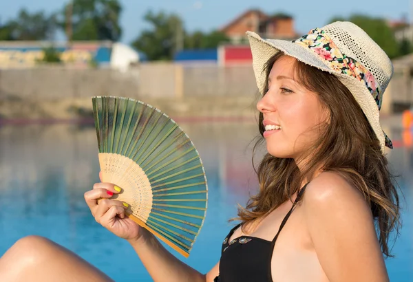 Dívka v bikinách držení rukou ventilátor u bazénu — Stock fotografie