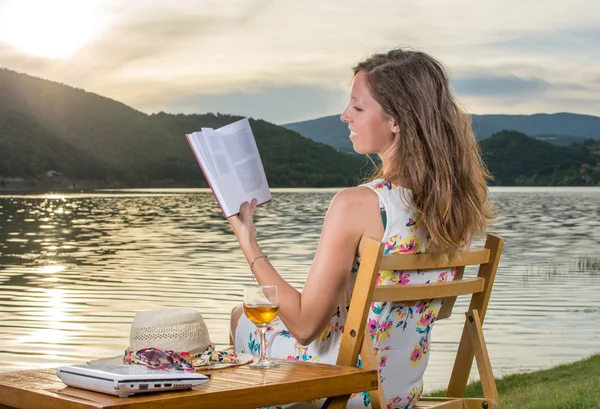 Mulher lendo um livro junto ao lago — Fotografia de Stock