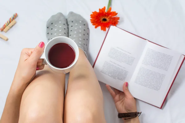 Frau liest ein Buch und trinkt Tee — Stockfoto