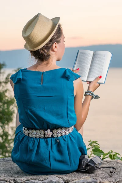 Mulher lendo um livro com uma vista do pôr do sol — Fotografia de Stock