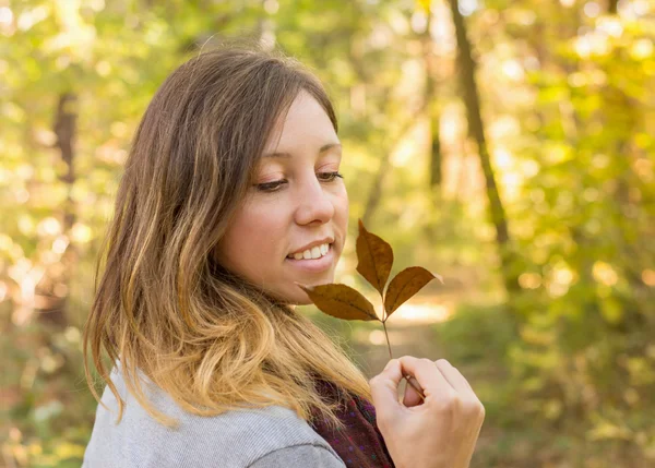 Mulher feliz segurando folha de outono no parque — Fotografia de Stock
