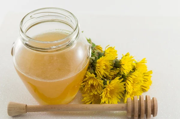 Jar of honey and yellow dandelion flower — Stock Photo, Image