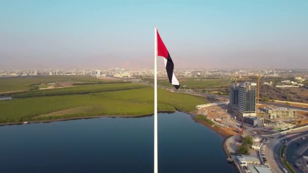 アラブ首長国連邦国旗竿とラアス ハイマ周辺の回転する景色は アラブ首長国連邦北部の空のスカイラインのランドマークとマングローブとコーニッチダウンタウンエリアの上のスカイラインの景色を記念しています — ストック動画
