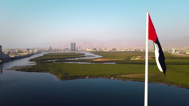 アラブ首長国連邦国旗ポールとラアス ハイマは アラブ首長国連邦北部の空のスカイラインのランドマークとマングローブとコーニッチ中心街の上空のスカイラインの景色を記念しています — ストック動画