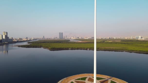 アラブ首長国連邦国旗ポールとラアス ハイマは アラブ首長国連邦北部の空のスカイラインのランドマークとマングローブとコーニッチ中心街の上空のスカイラインの景色を記念しています — ストック動画