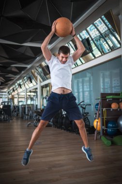 Man exercising in the gym jumping and slamming a heavy medicine slam ball for core strength exercise clipart