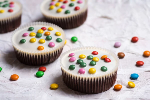 甜甜的松饼 白色的巧克力和糖果在白色基布的顶部视图 — 图库照片