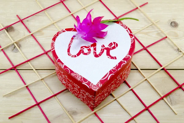 Καρδιά σχήμα κουτί διακοσμημένο με ένα ροζ λουλούδι — Φωτογραφία Αρχείου