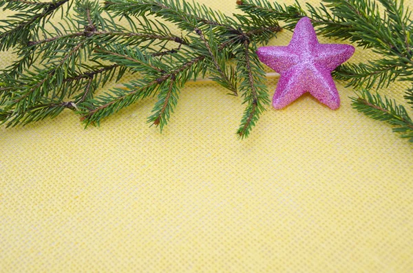 Pink star ornament met fir takken op geel — Stockfoto