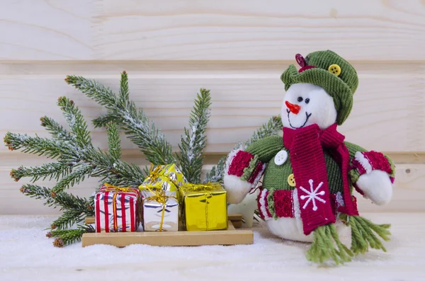 Juguete muñeco de nieve entre abetos y regalos — Foto de Stock