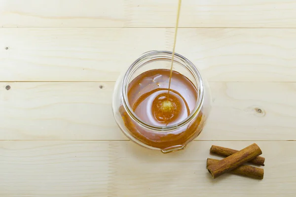 Honey dripping into a glass jar — Stock Photo, Image