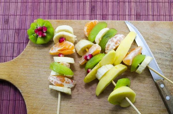 Varias frutas pinchadas en una tabla de cortar — Foto de Stock