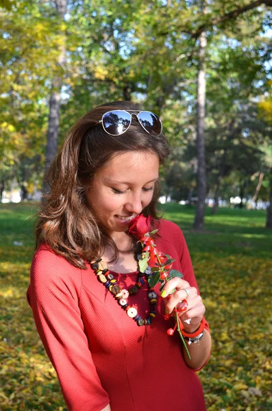 Ung vacker kvinna med en ros i en park — Stockfoto