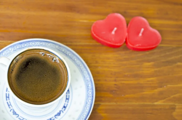 Tasse schwarzen Kaffee und Kerzen in Herzform — Stockfoto