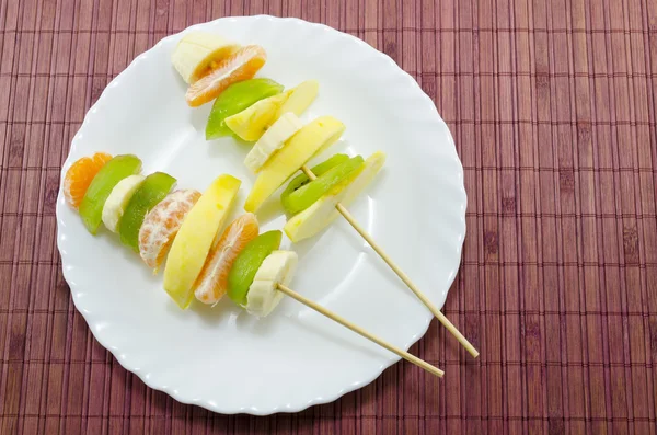 Deliciosas brochetas de frutas en un plato blanco — Foto de Stock