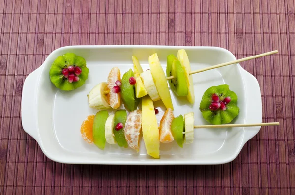 Dos pinchos llenos de fruta colorida en una mesa —  Fotos de Stock