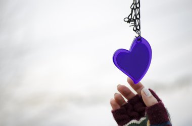 Woman hands in mittens reaching for a heart clipart
