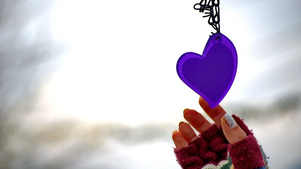 Woman hands in mittens reaching for a heart — Stock Photo, Image