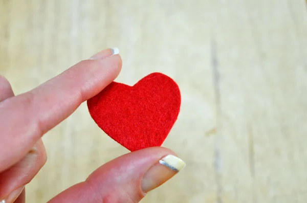 Pequeño corazón rojo sostenido por los dedos de las mujeres — Foto de Stock