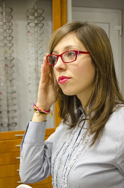 Молода брюнетка намагається окуляри в магазині оптики — стокове фото