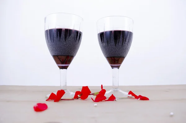 Dvě sklenky vína na stůl s okvětních lístků — Stock fotografie