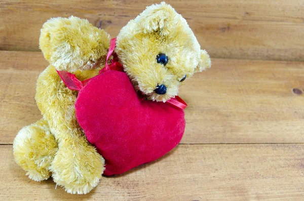 Big teddy bear lying on a red heart — Stock Photo, Image