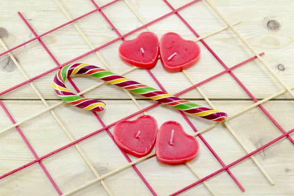 Red heart shaped candles and a candy cane — Stock Photo, Image