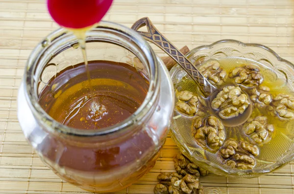 Walnuts and honey poured in a jar — Stock Photo, Image