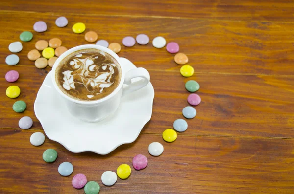 Tasse Kaffee auf einem Tisch mit bunten Bonbons — Stockfoto