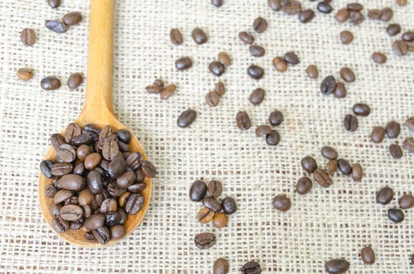Cuchara de madera llena de granos de café tostados — Foto de Stock