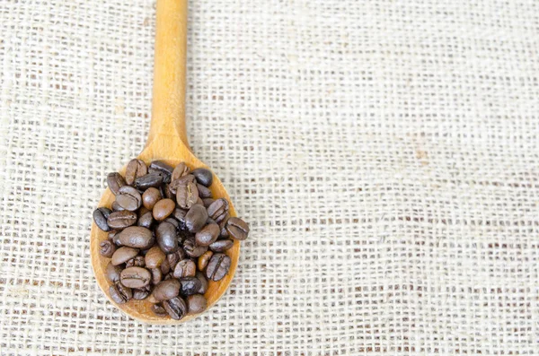 Cuchara de madera llena de granos de café tostados — Foto de Stock