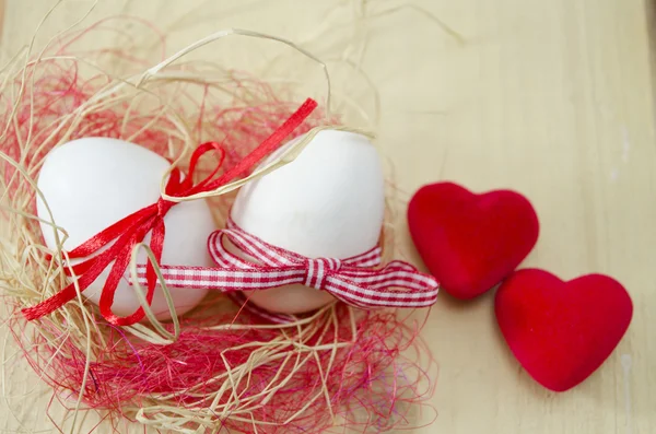 Dos huevos blancos en un nido y dos corazones — Foto de Stock