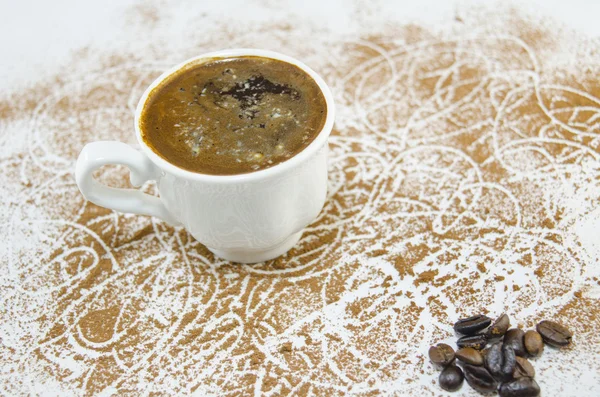 Tasse Kaffee auf einem mit Kaffeekörnern bedeckten Tisch — Stockfoto