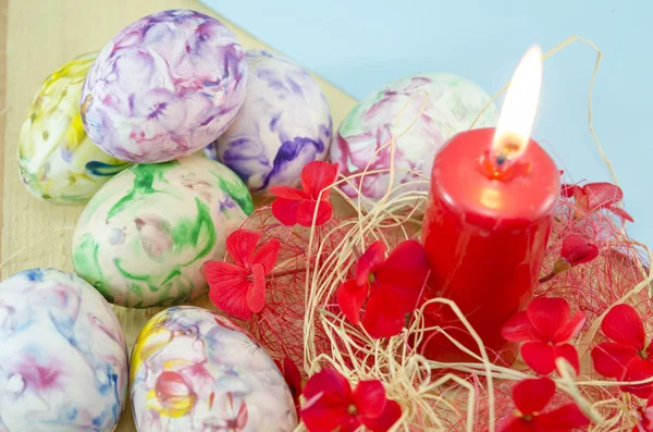 Docena de huevos de Pascua coloreados a mano y una vela encendida —  Fotos de Stock