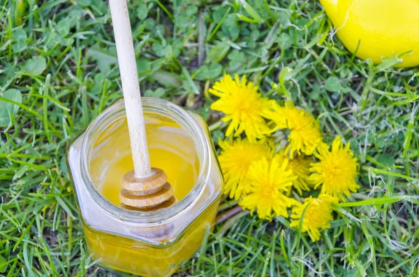 Tarro de miel, cazo, limón y flores amarillas en la hierba —  Fotos de Stock