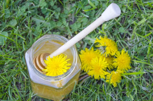 Jar of honey, dipper, lemon and yellow flowers in the grass — Stock Photo, Image